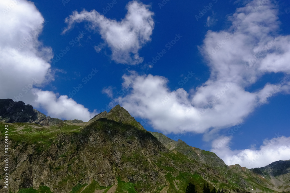 pointed mountain with wonderful soft white clouds on the sky