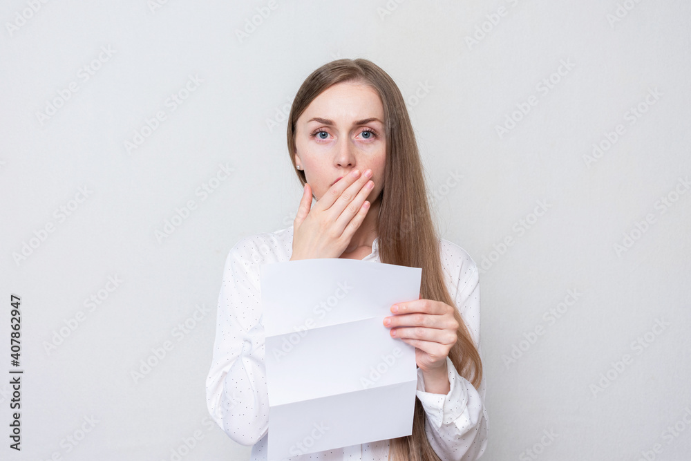 Portrait of a distressed woman reading a letter, a woman closes her mouth in surprise, white background Portrait of a distressed woman reading a letter, a woman closes her mouth in surprise, white background