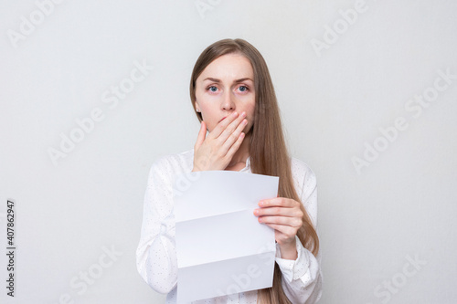 Portrait of a distressed woman reading a letter, a woman closes her mouth in surprise, white background