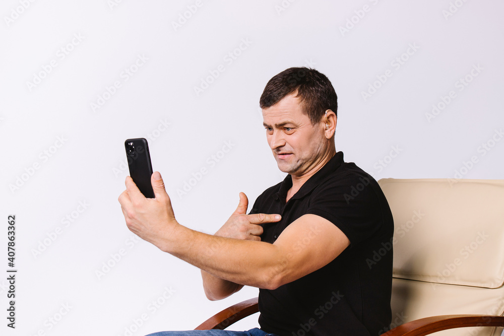 Senior hearing impaired man work in office, emotionally communicates with gestures via video call on smartphone on white background. Senior hearing impaired man work in office, emotionally communicates with gestures via video call on smartphone on white background.