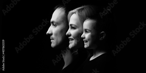 Joyful family mother, father and little girl in black clothes with dark background. Family portrait © Angelov