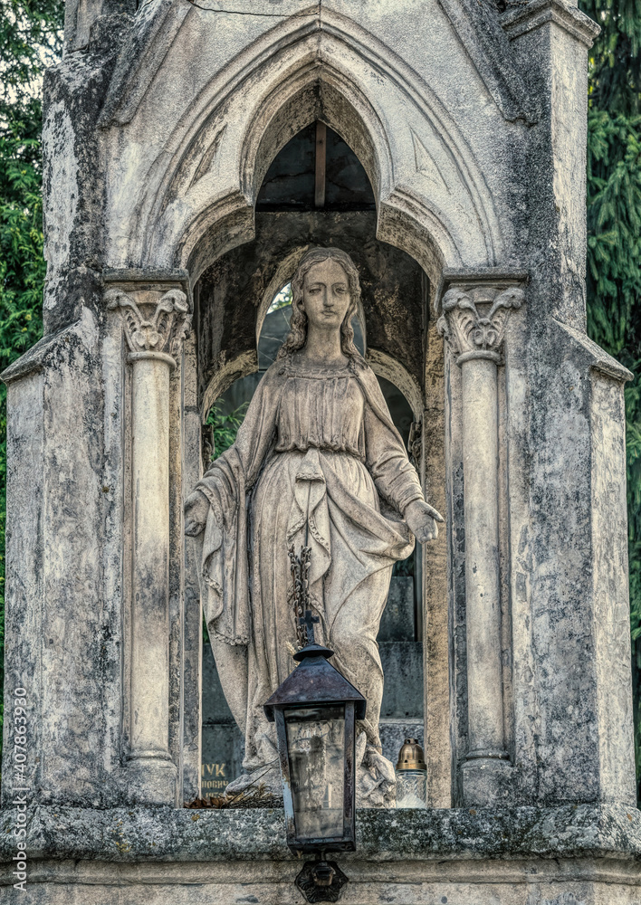 Lviv, Ukraine - July 12, 2019: Ancient gothic Lychakiv cemetery in Lviv, Ukraine. Ancient stone crypts, tombs and gravestones against the backdrop of overgrown green trees and herbs. Famous landmark