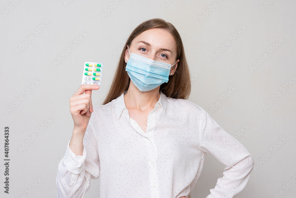 Cheerful young woman in medical mask shows a packaging pills, white background, health care concept Cheerful young woman in medical mask shows a packaging pills, white background, health care concept