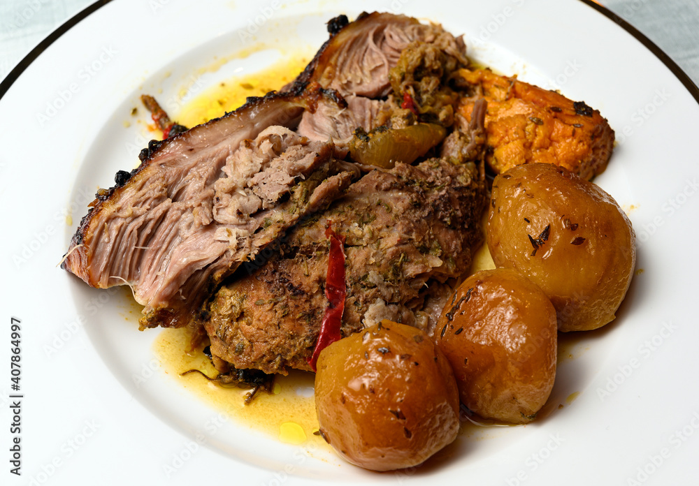 Portion of homemade roast pork with potatoes in white plate