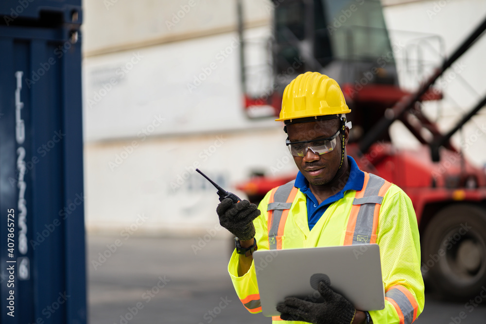 worker man in protective safety jumpsuit uniform with yellow hardhat and use laptop check container at cargo shipping warehouse. transportation import,export logistic industrial service worker man in protective safety jumpsuit uniform with yellow hardhat and use laptop check container at cargo shipping warehouse. transportation import,export logistic industrial service