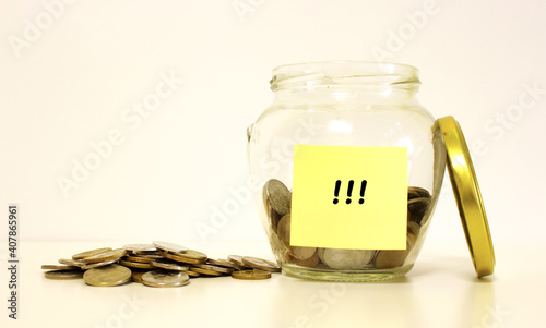 Glass jar with coins for savings. The inscription on the note paper.