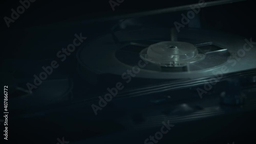 
Macro shots of a 1970s quarter-inch open-reel tape recorder in operation. Shallow depth of field with focus on the rotating spools. Suggestive of a wiretap or surveillance. 