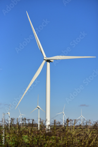 A large windmill against a blue sky, with other windmills in the background.