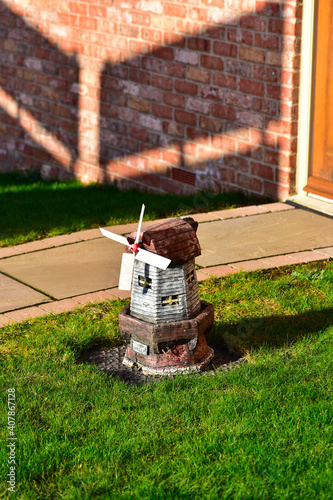 A small windmill on a green lawn.