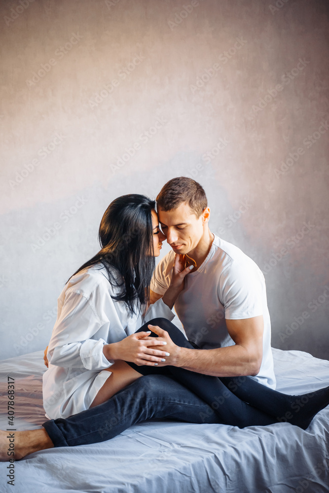 Beautiful passionate couple having sex on the bed. Cheerful romantic lovers hugging. The