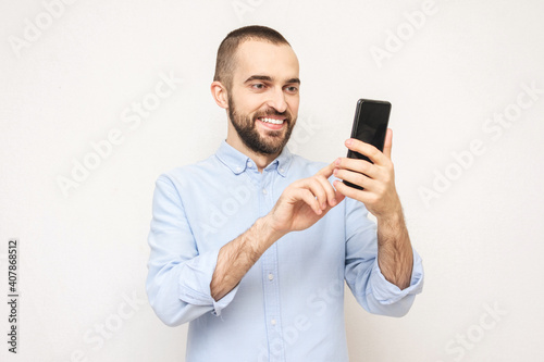Bearded uses phone, white background, copy space © Анастасия Семашко