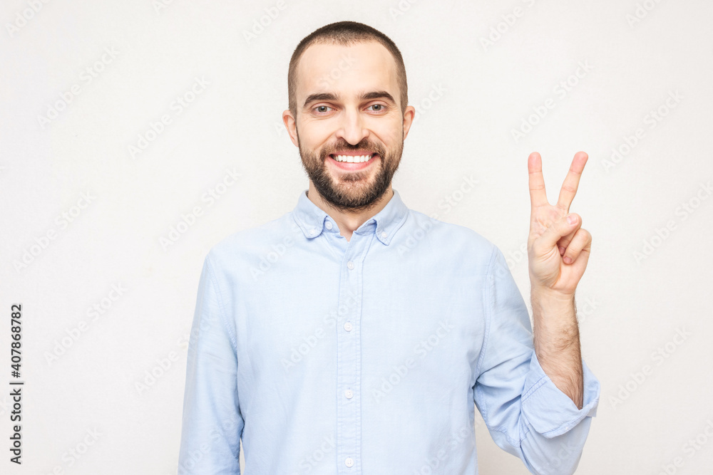 Bearded man shows sign peace with fingers, white background, copy space Bearded man shows sign peace with fingers, white background, copy space