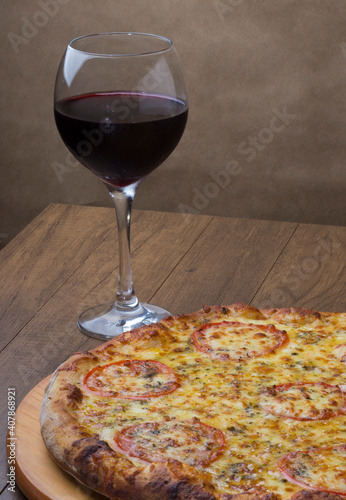ricardo fernando franca junior pizza mussarela muçarela mucarelTasty mozzarella cheese pizza with sliced ​​red tomatoes. A glass of red wine to accompany the meal. Vertical photography.