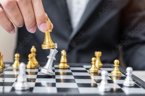 Fotografi businessman hand moving gold Chess King figure and Checkmate enermy or opponent during chessboard competition