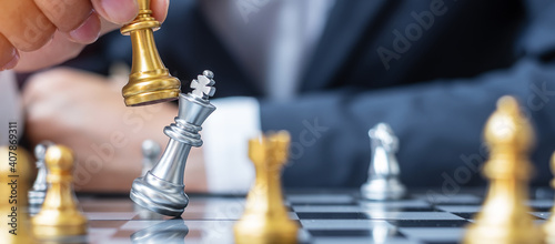 businessman hand moving gold Chess King figure and Checkmate enermy or opponent during chessboard competition. Strategy, Success, management, business planning, interruption and leadership concept photo