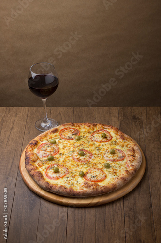 ricardo fernando franca junior pizza mussarela muçarela mucarelHigh angle photo highlighting the details of a mozzarella cheese pizza with sliced ​​red tomatoes. A glass of red wine. photo