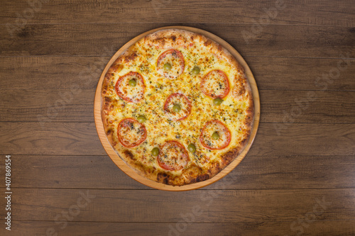 Delicious mozzarella cheese pizza with slices of red tomatoes on a wooden board. Top photograph with centralized food.