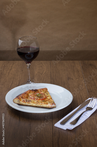 ricardo fernando franca junior pizza mussarela muçarela mucarelTasty slice of mozzarella cheese pizza with slices of red tomatoes. A glass of red wine to accompany the meal. Gastronomic photography. photo