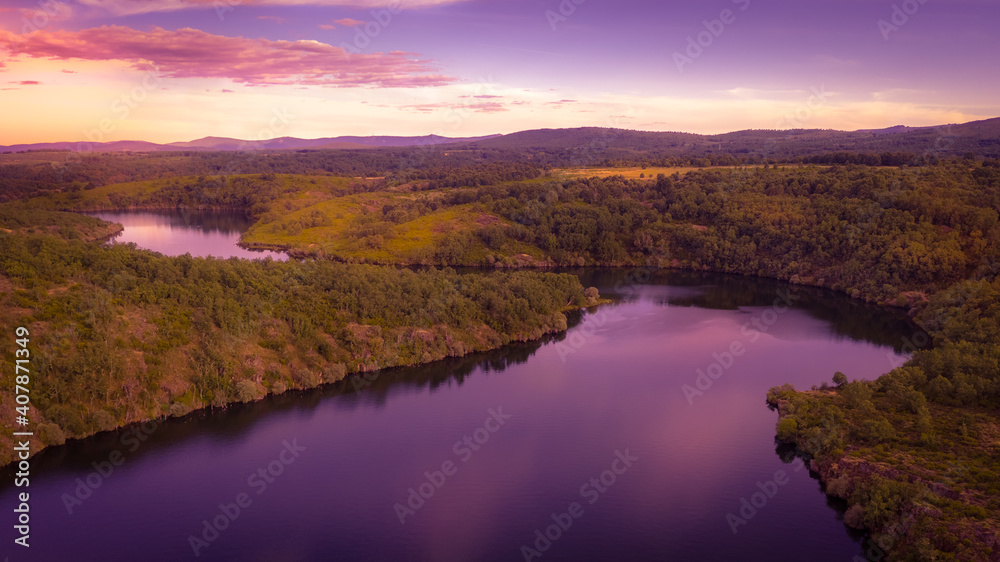 aerial view, river going through forest with the sky at sunset