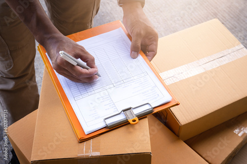 Warehouse worker writing paper on clipboard. inventory management of product. packaging boxes. checking stock. parcel shipment boxes. photo