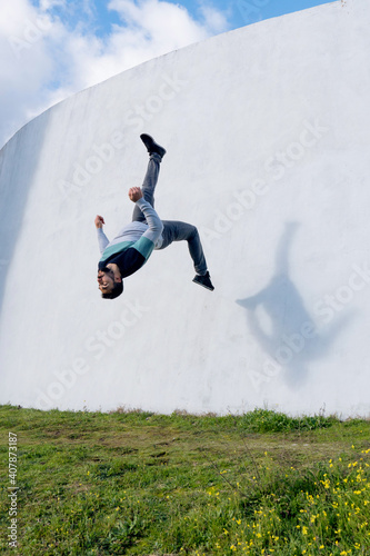 parkour jump in the air young and strong Caucasian boy outfit urban sport sweatshirt colors and blue sky free running street stun