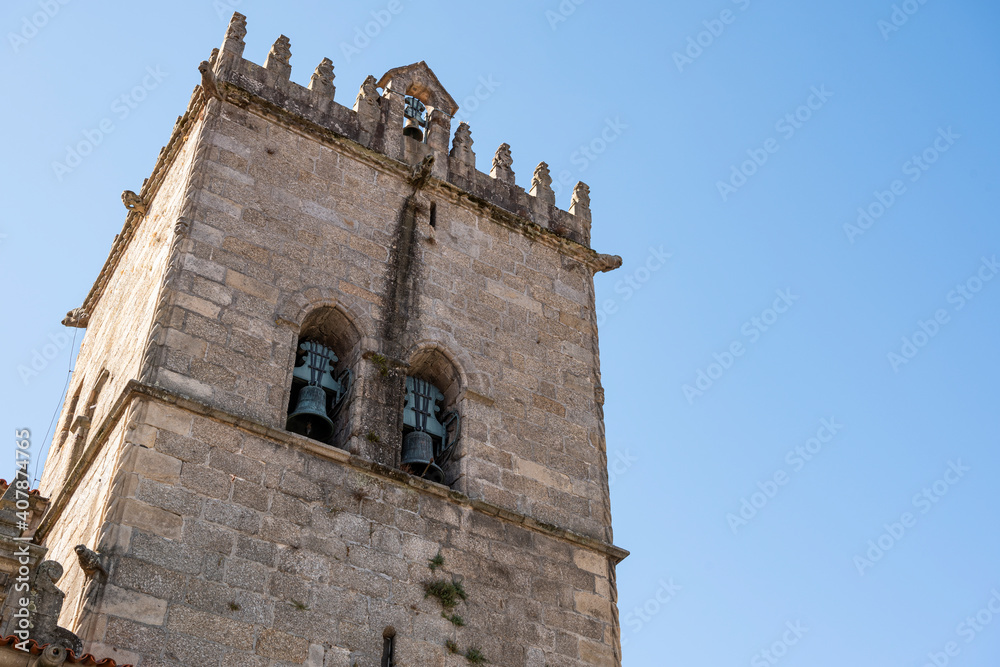 Church tower with bells. Exterior of Nossa Senhora da Oliveira Church. Old medieval building. Blue sky.
