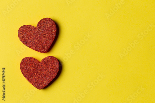 top view of two Red heart-shaped on a yellow paper background