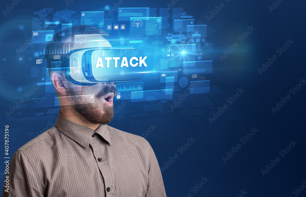 Businessman looking through Virtual Reality glasses with ATTACK inscription, innovative security concept Businessman looking through Virtual Reality glasses with ATTACK inscription, innovative security concept