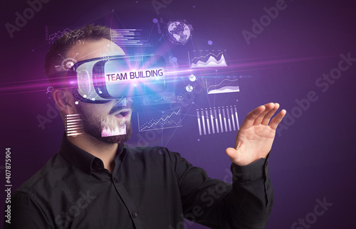 Businessman looking through Virtual Reality glasses with TEAM BUILDING inscription, new business concept