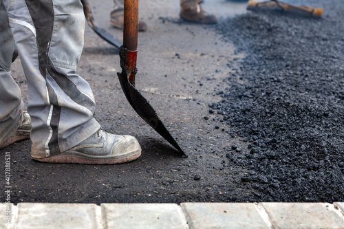 Aufbringen von Asphalt in Handarbeit bei dem Bau einer Straße