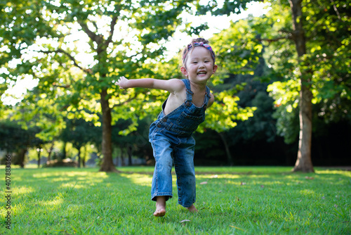 芝生で遊ぶオーバーオールを着た女の子