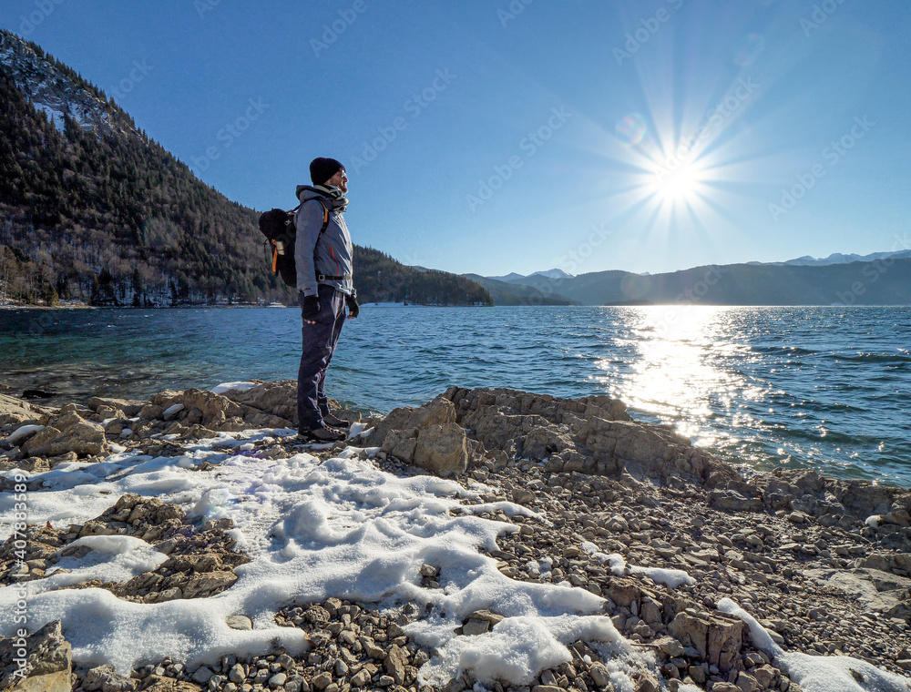 Happy Man hike along a Bavarian lake during blue sky sunshine