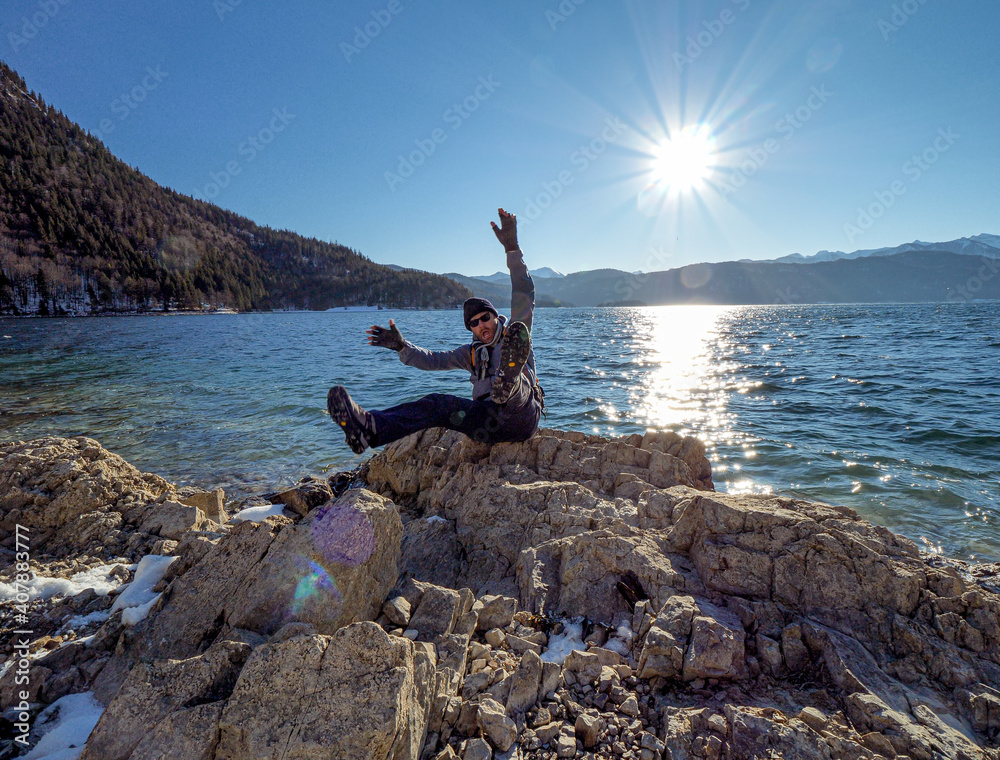 Happy Man hike along a Bavarian lake during blue sky sunshine