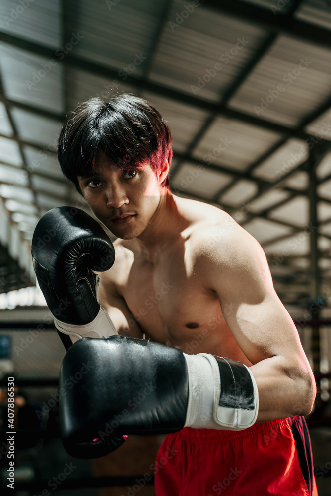 close up of sportsman muay thai boxer fighting in gloves in boxing cage