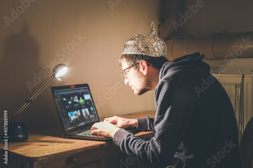 Foto Conspiracy theory concept: young man with aluminum cap searching the internet, s