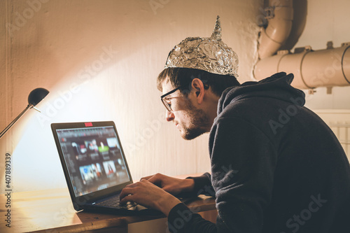 Bild auf Leinwand Conspiracy theory concept: young man with aluminum cap searching the internet, s
