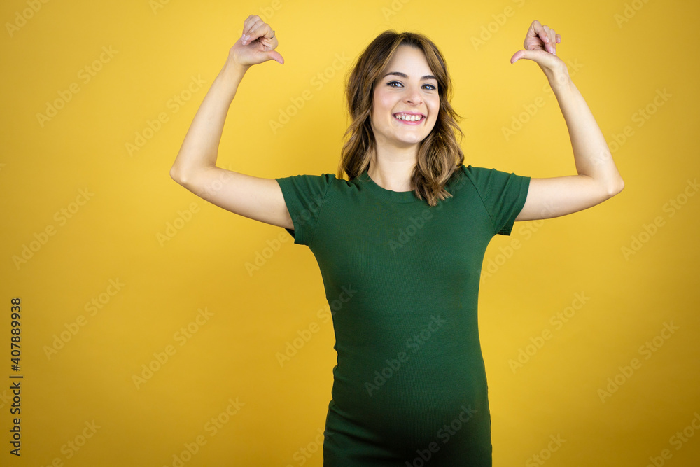 Young beautiful brunette woman pregnant expecting baby over isolated yellow background looking confident with smile on face, pointing oneself with fingers proud and happy. Young beautiful brunette woman pregnant expecting baby over isolated yellow background looking confident with smile on face, pointing oneself with fingers proud and happy.