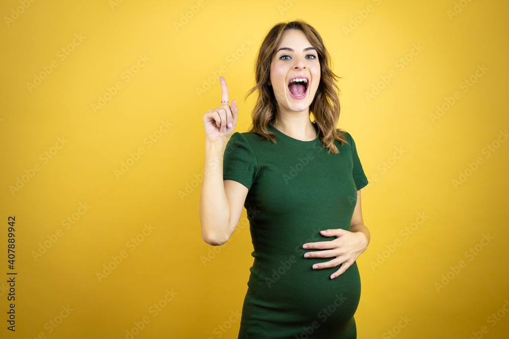 Young beautiful brunette woman pregnant expecting baby over isolated yellow background surprised and thinking with her finger on her head that she has an idea. Young beautiful brunette woman pregnant expecting baby over isolated yellow background surprised and thinking with her finger on her head that she has an idea.