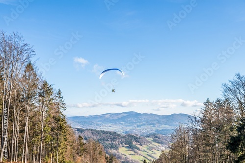 Fliegender Hobby Gleitschirm Flieger an einem Berghang mit professioneller Ausrüstung im Herbst mit Aussicht auf Berge und Alpen im Hintergrund, Deutschland photo