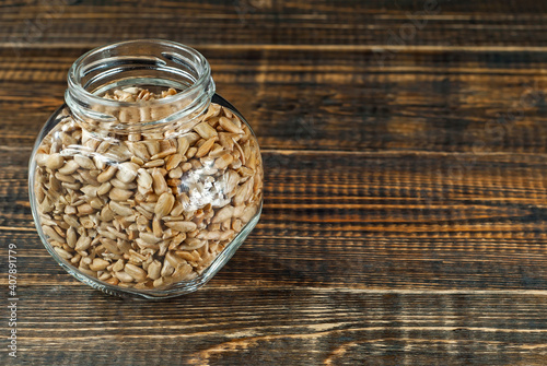 Sunflower seeds in a glass transparent jar. Nuts on an old shabby board. Jar on a brown wooden table close up. photo