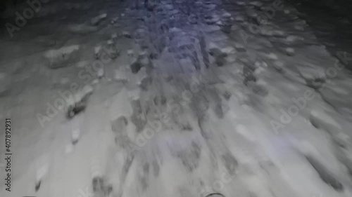 Cyclist Riding the Mountain Bike on the snowy Trail at Night. Extreme Sport and Enduro Biking Concept. Snowy and slippery road covered by few centimetres of sticky snow