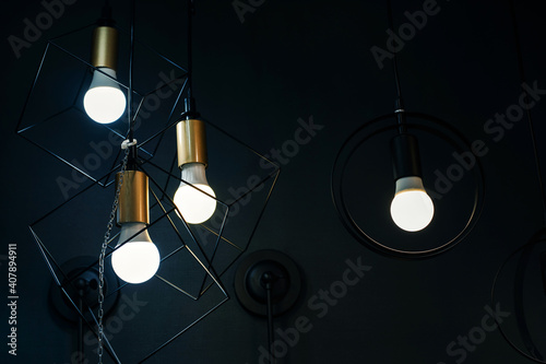 Decorative chandeliers made of metal rods in the form of a square and a circle on a dark background. Unusual ideas for decorating living space in the house