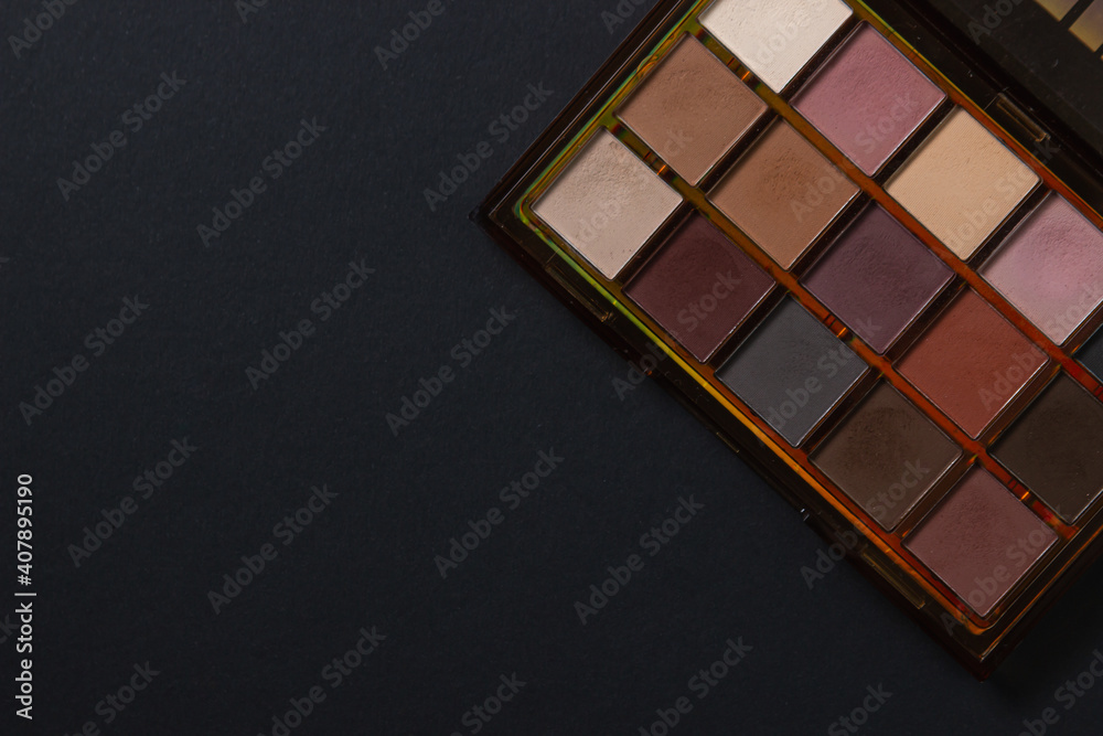Fototapeta premium A palette of cosmetics. Cosmetics on a black background. Warm eye shadow.