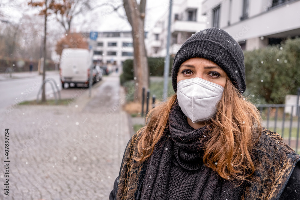 Plakat young brunette woman outdoors in the cold wearing a ffps mask