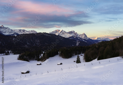 Beautiful sunrise in the mountains with snow covered huts in foreground - Alps with Alpspitze and Zugspitze in background