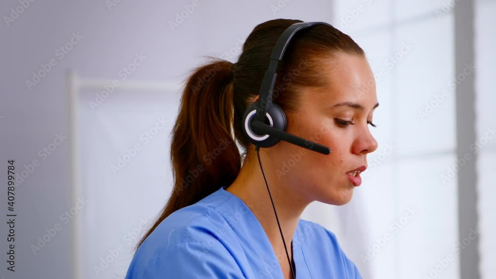 Portrait of medical receptionist answering pressing on headphone helping patient making appointment in hospital. Healthcare physician in medicine uniform, doctor assistant during telehealth Portrait of medical receptionist answering pressing on headphone helping patient making appointment in hospital. Healthcare physician in medicine uniform, doctor assistant during telehealth