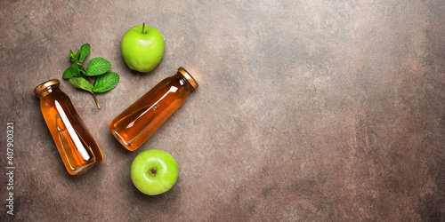 Apple juice in a bottle, green apple and fresh mint leaves on a dark rustic background, banner. Top view, flat lay, copy space.