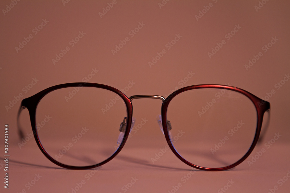 Elegante, trendige, weinrote Damenbrille auf pastellrosa Hintergrund