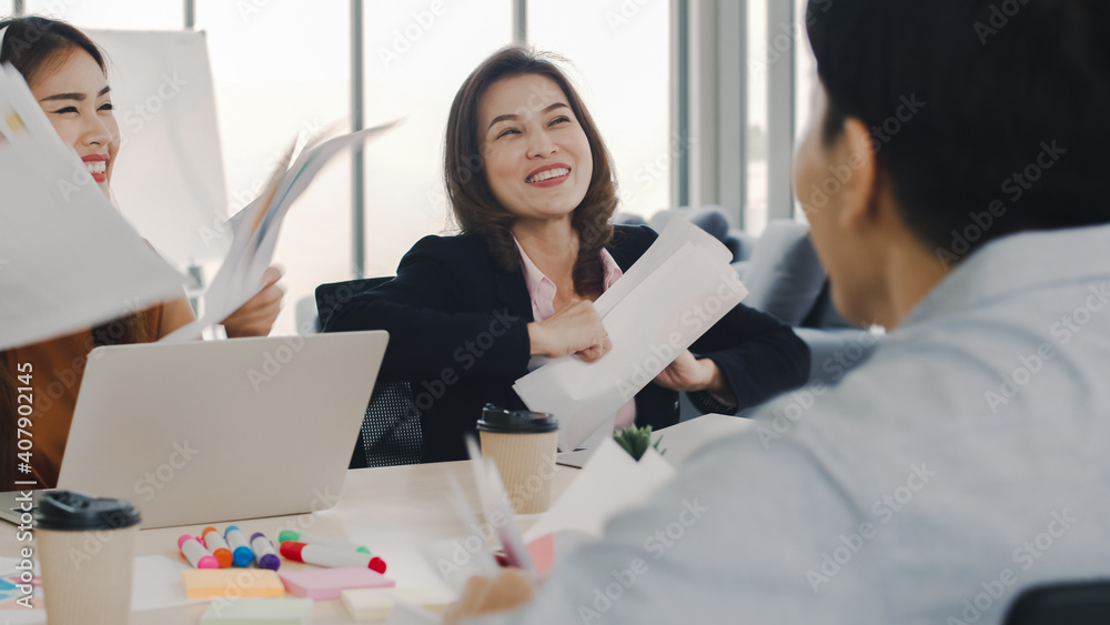 Group of Asian business team people throwing documents celebrating success at their working places in the modern office. Group of Asian business team people throwing documents celebrating success at their working places in the modern office.