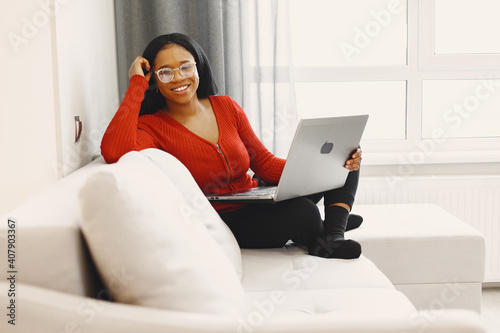 Woman with a laptop. International girl on a bed. Lady working.